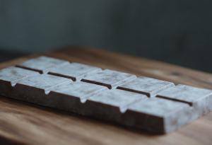Barra de chocolate com manchas esbranquiçadas de fat bloom na superfície, sem brilho