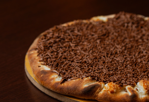 Pizza doce finalizada com cobertura sobre a massa recém-saída do forno